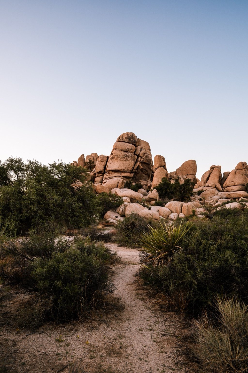 Desert trail leading toward a towering rock formation under a wide open sky